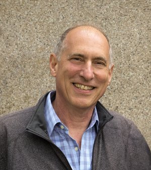 A headshot of a smiling, balding man.