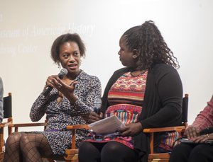 Two women in a panel speaking before an audience.