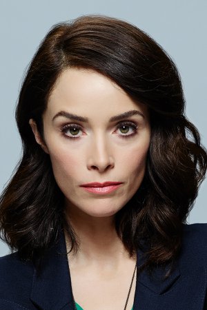 A headshot of a woman with dark, wavy, shoulder-length hair.